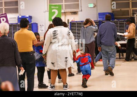 Baltimore, États-Unis. 31 octobre 2024. 31 octobre 2024, Baltimore City, Maryland, États-Unis. De très longues files de personnes attendant de voter la dernière nuit du vote anticipé à l'élection présidentielle de 2024. Tous les électeurs en ligne à 20 heures HNE allaient voter. Certaines personnes portaient des costumes d'Halloween. Beaucoup de gens ont amené leurs enfants à témoigner de cette élection historique où les sondages sont très proches. (Photo de Robyn Stevens Brody/Sipa USA) crédit : Sipa USA/Alamy Live News Banque D'Images