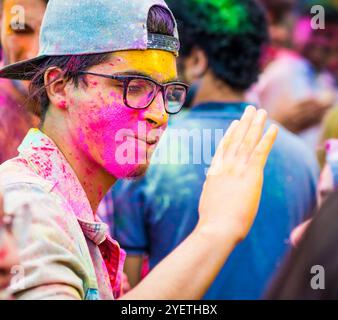 Khakiv, Ukraine - 19 mai 2018 : Portrait d'un jeune homme souriant dans des lunettes avec de la poudre Holi colorée sur son visage. Fête de la couleur Holi célébrant Banque D'Images