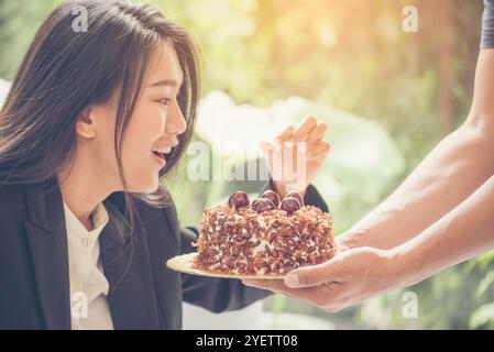 Le visage de la jeune femme asiatique a reçu un gâteau surprise lors de son anniversaire. Elle se sent excite et heureuse. Banque D'Images