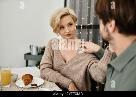 Un couple profite d'un petit déjeuner chaud à la maison, partageant des sourires et des moments tendres autour de la nourriture. Banque D'Images