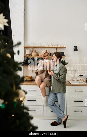 Un couple profite d'une boisson chaude ensemble dans leur cuisine élégante, créant une atmosphère amoureuse. Banque D'Images