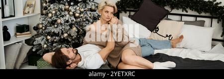 Un couple profite d'un moment tendre ensemble dans un salon cosy orné pour les vacances. Banque D'Images