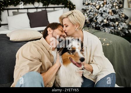 Un couple aimant s'embrasse tandis que leur chien interagit joyeusement dans un cadre confortable. Banque D'Images