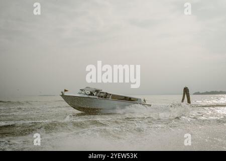 Venise, Vento – IT – 13 octobre 2024 un élégant bateau-taxi qui accélère à travers le lagon de Venise, créant des vagues dans son sillage. Le bateau coupe à travers l'eau und Banque D'Images