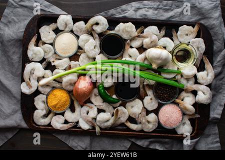 Tom Rim (crevettes caramélisées vietnamiennes) ingrédients sur un plat : crevettes congelées avec sauce de poisson, échalotes, et plus sur une plaque de cuisson rustique Banque D'Images