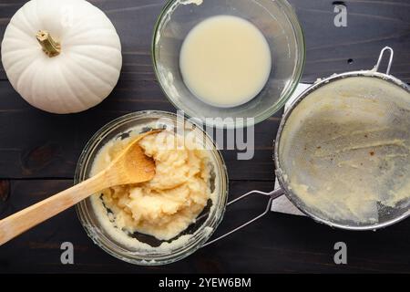 Purée de citrouille blanche maison dans un bol à mélanger en verre : bol de citrouille boule de neige fraîchement rôtie, égouttée et purée avec une passoire et une cuillère en bois Banque D'Images