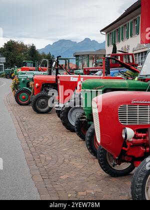 Vieux tracteurs garés en rangée. Tracteurs rouges et verts vintage placés le long de la route après le festival de rassemblement des agriculteurs. Banque D'Images