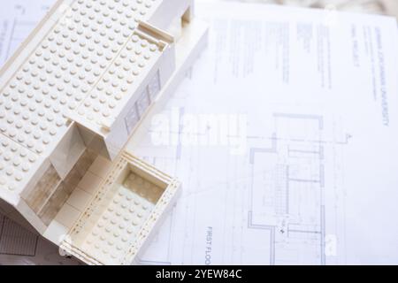 Un modèle architectural miniature moderne ressemblant à une maison se trouve sur des plans d'étage détaillés, illustrant le design et la créativité dans l'architecture et la construction Banque D'Images