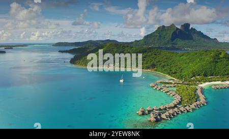 Eau de lagon turquoise, bungalows sur l'eau et montagnes verdoyantes de l'île tropicale de Bora Bora en Polynésie française. Fond de voyage de vacances d'été exotiques de nature sauvage à distance. Prise de vue aérienne par drone Banque D'Images