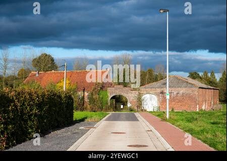 Vue en perspective sur une ancienne ferme en pierre de brique dans la campagne flamande à Sint Martens Lennik, Brabant flamand, Belgique Banque D'Images