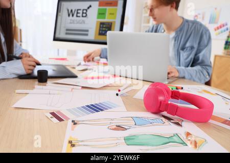 Écouteurs avec des dessins sur la table contre couple de graphistes travaillant dans le bureau, gros plan Banque D'Images