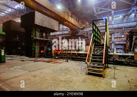 Barre en acier chaud de l'usine de métal laminé sur le convoyeur se déplaçant à travers les rouleaux. Banque D'Images