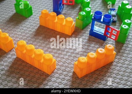 Blocs de construction en plastique coloré disposés sur un tapis, créant une configuration ludique. Banque D'Images