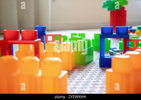 Blocs de construction en plastique coloré disposés sur un tapis, créant une configuration ludique. Banque D'Images