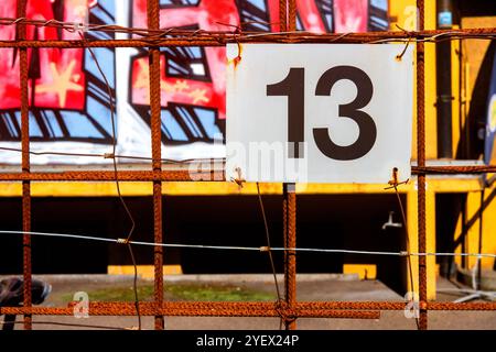 Signe en métal avec le numéro 13 attaché au fer rouillé avec graffiti en arrière-plan Banque D'Images