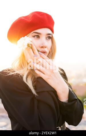Belle femme en béret rouge tenant la fleur blanche Banque D'Images