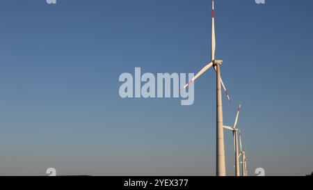 rangée de générateurs de vent debout sur le côté droit de la bannière avec fond bleu de ciel clair, moulins à vent avec de grandes pales sur le fond Banque D'Images