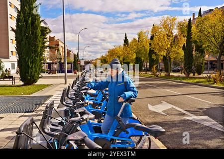 Une femme se tient devant une rangée de vélos. Les vélos sont garés en rangée sur le bord de la route Banque D'Images