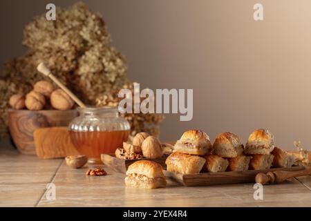 Baklava avec noix et miel sur fond beige. Désert oriental traditionnel dans un plat en bois. Copier l'espace. Banque D'Images