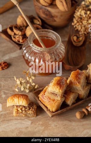 Baklava avec noix et miel sur fond beige. Désert oriental traditionnel dans un plat en bois. Banque D'Images