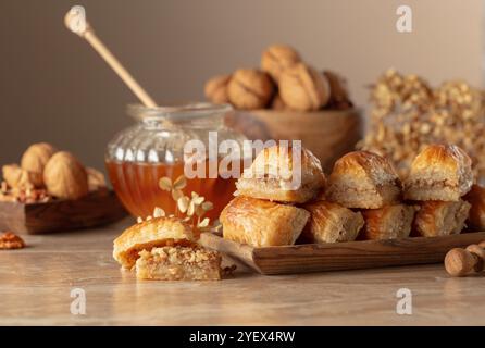 Baklava avec noix et miel sur fond beige. Désert oriental traditionnel dans un plat en bois. Copier l'espace. Banque D'Images