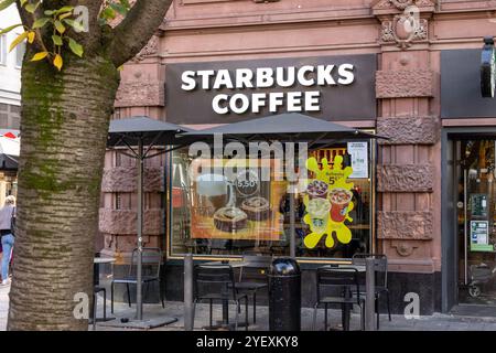 Francfort Allemagne - 26 octobre 2024 : un café Starbucks animé propose des sièges extérieurs avec des parasols, des publicités colorées et Banque D'Images