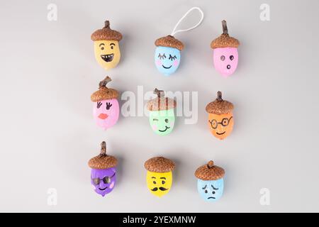 Glands colorés avec des visages emoji sur fond gris. Idée artisanale de bricolage d'automne, pose à plat. Parfait pour l'activité des enfants, bricolage, artisanat, vue de dessus Banque D'Images