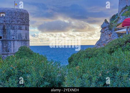 Coucher de soleil sur la mer et les murs de la vieille ville avec un ciel orageux et un horizon nuageux. Banque D'Images