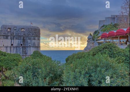 Coucher de soleil sur la mer et les murs de la vieille ville avec un ciel orageux et un horizon nuageux. Banque D'Images