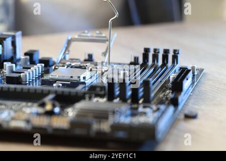 Carte mère avec puce informatique moderne et d'autres composants sur table en bois, gros plan Banque D'Images
