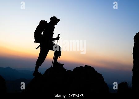 Silhouette de grimpeurs montant une montagne accidentée, les gens sur l'escalade de montagne de pic aidant le travail d'équipe, voyage trekking succès concept d'affaires. Banque D'Images