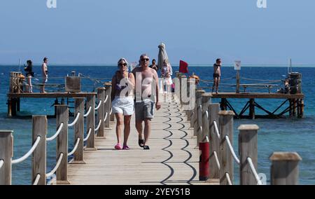 Tourisme en Egypte les touristes marchent sur une marina dans la station balnéaire égyptienne de la mer Rouge d'Al-Gouna, à 500 km au sud du Caire le 31 octobre 2024. L'industrie touristique égyptienne a connu une forte hausse en 2024, s'appuyant sur des chiffres record de 2023. Rien qu’au cours du premier semestre de 2024, l’Égypte a accueilli environ 7,1 millions de touristes, avec des revenus de l’industrie atteignant 6,6 milliards de dollars, soit une augmentation de 5 % par rapport à la même période en 2023. Cette croissance a été stimulée par des efforts stratégiques, tels que l'introduction d'un nouveau visa quinquennal à entrées multiples et l'élargissement des liaisons aériennes, en particulier à partir de marchés clés comme la Chine et le Japon Banque D'Images