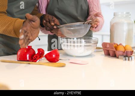 couple multiracial cuisiner ensemble dans la cuisine, tamiser la farine dans un bol en verre, à la maison Banque D'Images