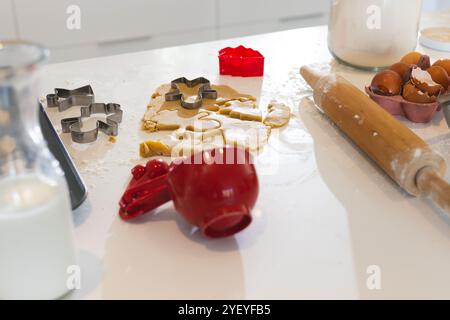 Cuisson de biscuits de Noël avec emporte-pièces et rouleau à pâtisserie sur le comptoir de cuisine, à la maison Banque D'Images