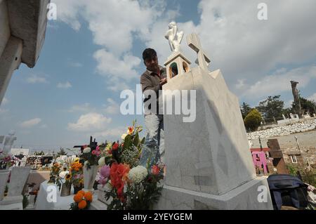 Amealco de Bonfil, Mexique. 01 novembre 2024. Une personne décore les tombes de ses proches avec des fleurs de cempasuchil et tient une veillée au cimetière municipal d'Amealco de Bonfil. Dans le cadre des traditions mexicaines du jour des morts, les gens visitent les tombes de leurs défunts pour passer du temps avec eux, selon les croyances les âmes des défunts rentrent chez eux pour passer du temps avec leurs proches et se nourrir avec la nourriture qui leur est offerte. Le 1er novembre 2024 à Amealco de Bonfil, Mexique. (Photo de Fernando Camacho/ crédit : Eyepix Group/Alamy Live News Banque D'Images