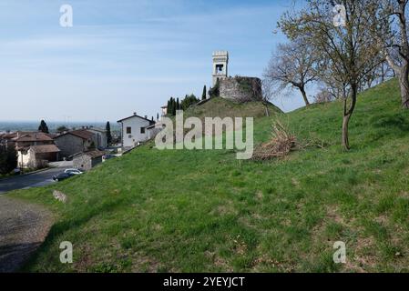 Pente en bas de la colline du château de Fagagna dans le Frioul (Italie) avec des arbres, un parking et des voitures garées. C'est une matinée ensoleillée de l'été Banque D'Images