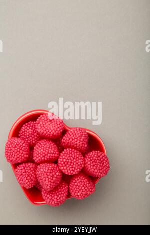 Bonbons à la framboise et à la mûre sur bol sur fond gris. Photo verticale Banque D'Images