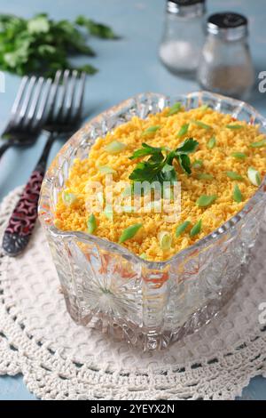 Salade festive Mimosa avec poisson en conserve, pommes de terre, fromage, carottes et œufs dans un saladier transparent Banque D'Images