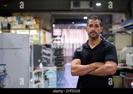 Portrait d'ingénieur industriel posant les bras croisés dans un atelier d'usine Banque D'Images