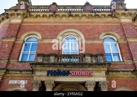 Leeds Angleterre : 2 juin 2024 : bâtiment historique en briques avec des sons plus riches signalétiques dans une ville avec des détails architecturaux ornés pendant une journée ensoleillée Banque D'Images