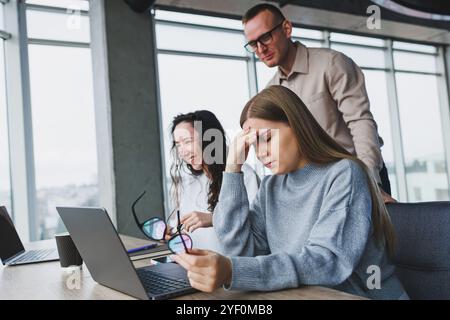 Jeune femme d'affaires tapant sur un clavier, recherchant des conceptions numériques pour un nouveau projet publicitaire, assis dans un bureau chic. Mal de tête dû au travail Banque D'Images