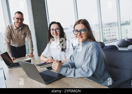 Jeune femme d'affaires tapant sur un clavier, recherchant des conceptions numériques pour un nouveau projet publicitaire, assis dans un bureau chic. Mal de tête dû au travail Banque D'Images