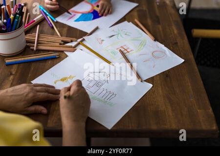 Vue de dessus d'une charmante fille et sa grand-mère créant joyeusement de l'art dans un album avec des crayons vibrants. Photo de haute qualité Banque D'Images