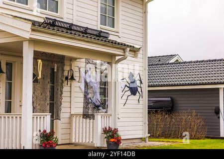 Décorations d'Halloween avec des pièces de squelette suspendues, des toiles d'araignée et une grande araignée sur l'extérieur de la maison. Banque D'Images