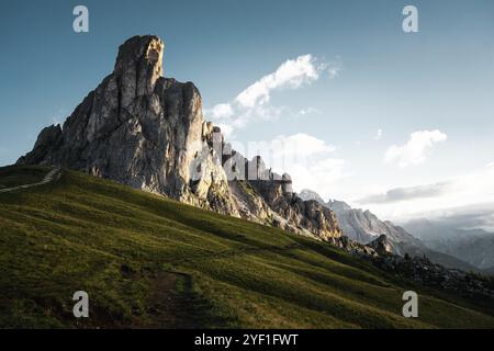 Une montagne majestueuse se dresse sur fond d'un ciel bleu brillant, avec des nuages blancs pelucheux dérivant paresseusement derrière elle, créant une vue imprenable Banque D'Images