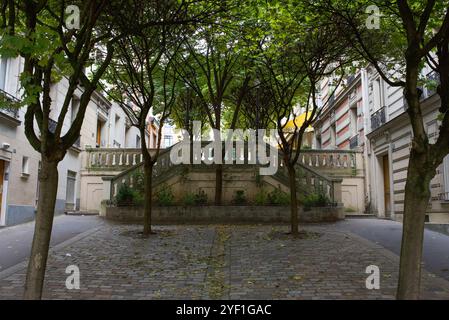 Paris, France, 10.31.2024 Une petite place résidentielle avec des arbres et des escaliers menant à une autre rue de Montmartre. Banque D'Images