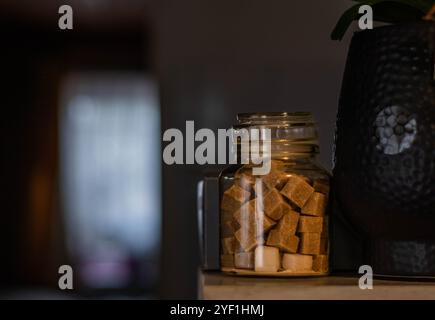 Cubes de sucre brun dans un pot à la lumière de la pièce orange Banque D'Images