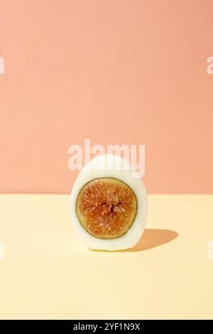 La moitié d'un oeuf dur fait de blancs et une figue sur fond rose. Pose à plat Banque D'Images