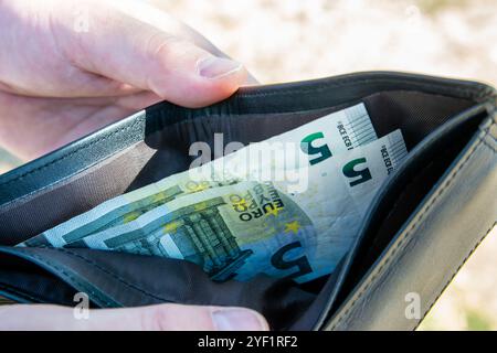 Homme tenant le chef noir partmone avec de l'argent en euros dans les mains. Billets dans le portefeuille pour le concept de commerce. Banque D'Images