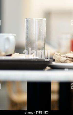 Tasse et verre sales dans la mise au point sélective à côté de quelques serviettes froissées brunes. Banque D'Images